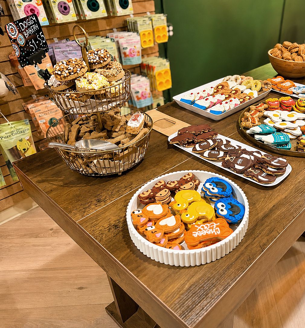 The doggy bakery table at PawSnickety East Lansing, with decorated dog cookies and a $1 to $5 sign