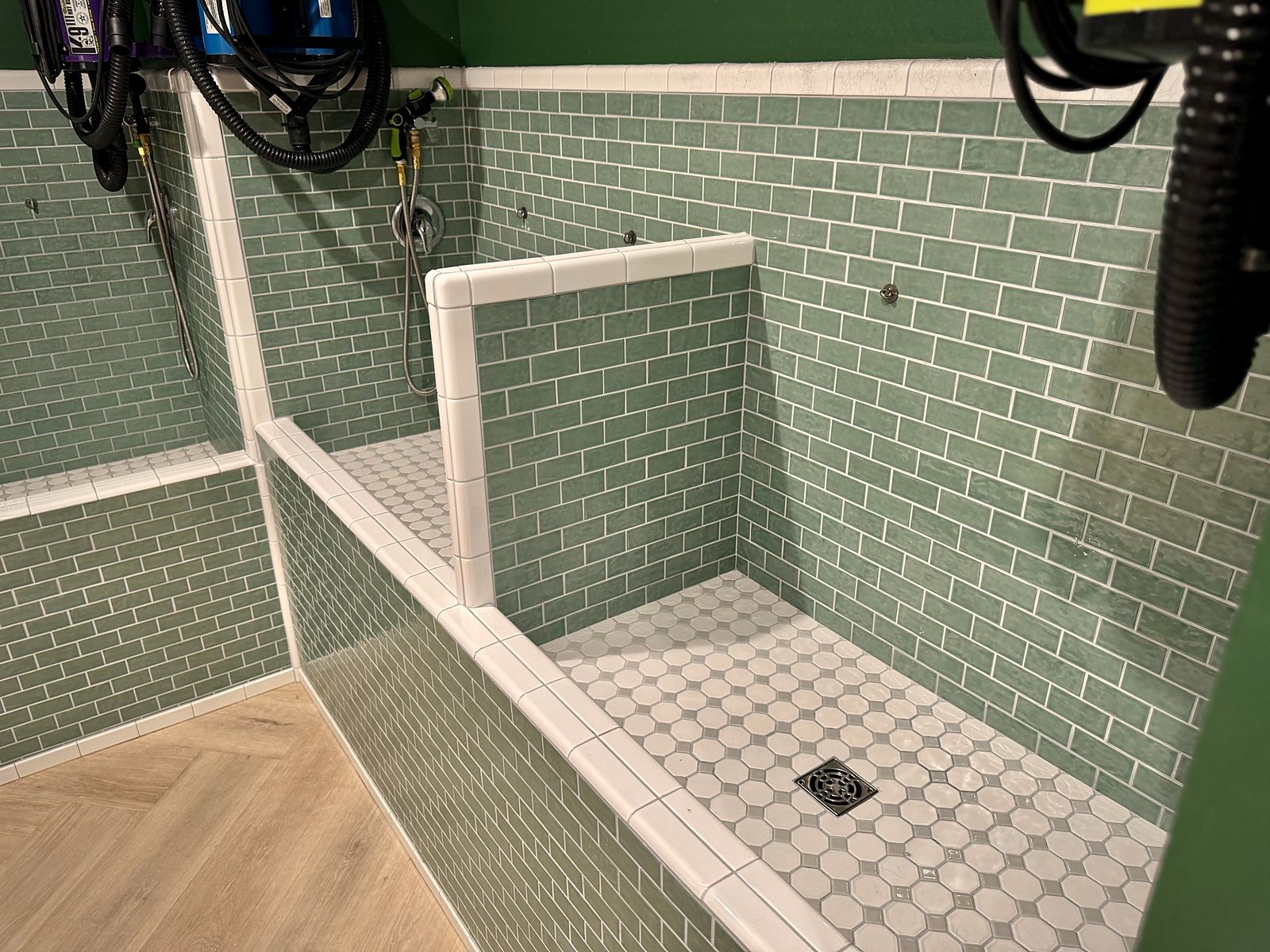 Tub room with green subway-tile tubs, a mosaic floor and wall-mounted dryers