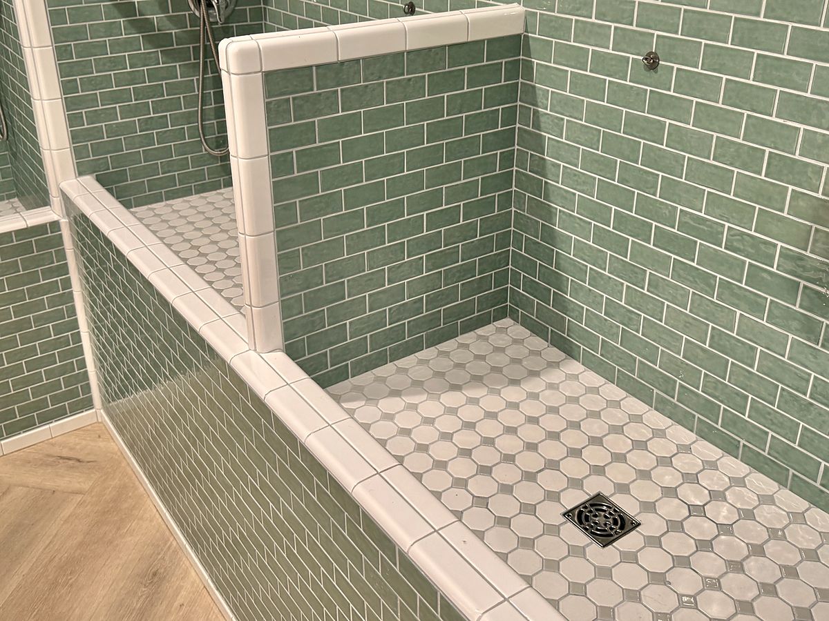 A tiled tub with white trim and an octagon mosaic floor